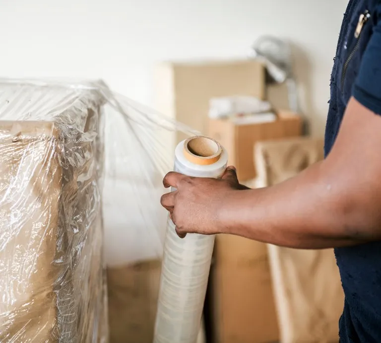 Mover wrapping furniture in stretch wrap