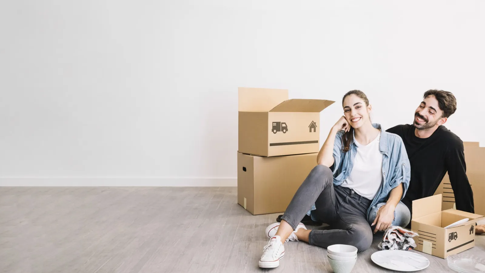Couple relaxing on the floor of their new apartment with moving boxes