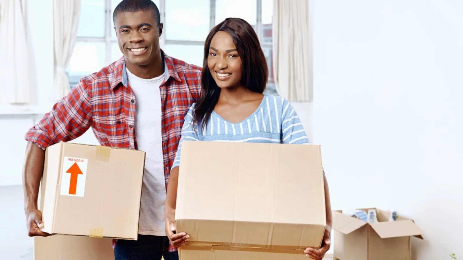 Smiling couple carrying moving boxes into their new home